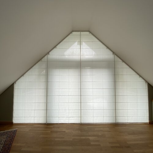 Maßgefertigte Biesenfaltrollos für schräge Fenster in einem lichtdurchfluteten Dachgeschoss.