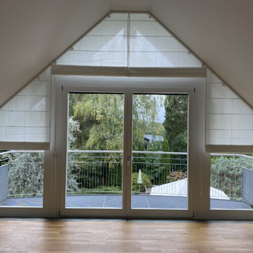 Maßgefertigte Biesenfaltrollos für schräge Fenster in einem lichtdurchfluteten Dachgeschoss.