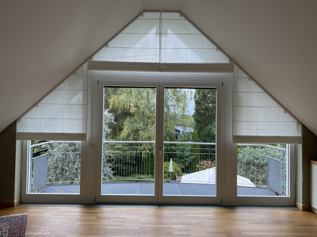 Maßgefertigte Biesenfaltrollos für schräge Fenster in einem lichtdurchfluteten Dachgeschoss.