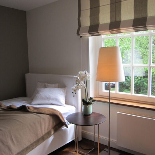 Quadro Faltrollo mit breiten Blockstreifen in einem gemütlichen Schlafzimmer mit natürlicher Farbgebung.