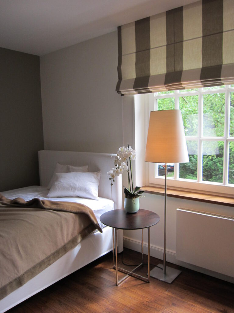Quadro Faltrollo mit breiten Blockstreifen in einem gemütlichen Schlafzimmer mit natürlicher Farbgebung.