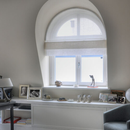 Maßgefertigtes Biesenfaltrollo für ein Rundbogenfenster, stilvolle Fensterdekoration mit lichtdurchlässigem Stoff.