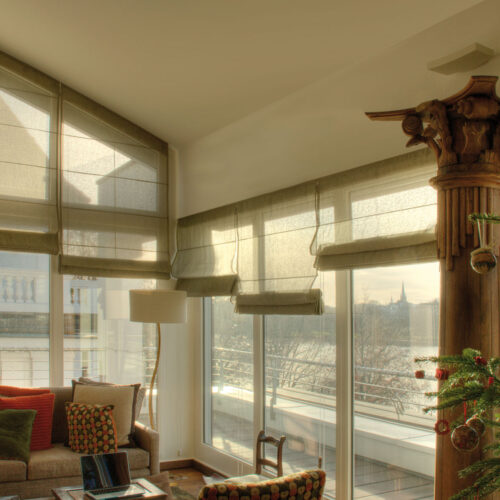 Maßgefertigte Biesenfaltrollos in warmem Naturton, perfekt abgestimmt auf schräge und gerade Fenster in einem lichtdurchfluteten Wohnraum.