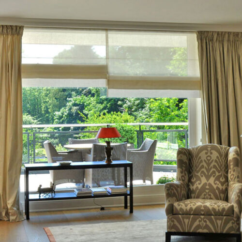 Elegante Vorhänge mit Biesenfaltrollos und großzügigem geradem Rolloabschluss in einem stilvollen Wohnraum.