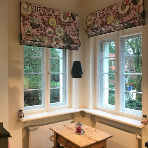 Gefütterte Quadro Faltrollos mit buntem Druckmotiv und eleganter schwarzer Einfassung.