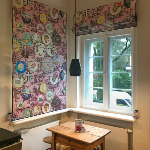 Gefütterte Quadro Faltrollos mit buntem Druckmotiv und eleganter schwarzer Einfassung.