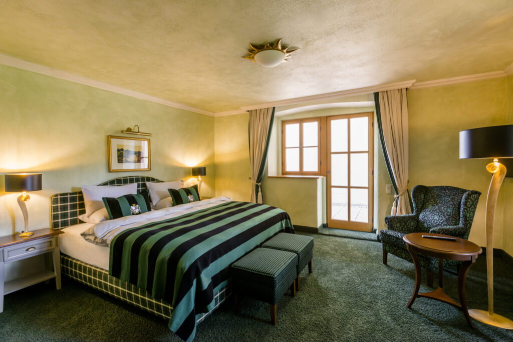 Elegantes Schlosshotel-Zimmer mit luxuriösem Bett, opulenten Vorhängen und stilvoller Einrichtung.