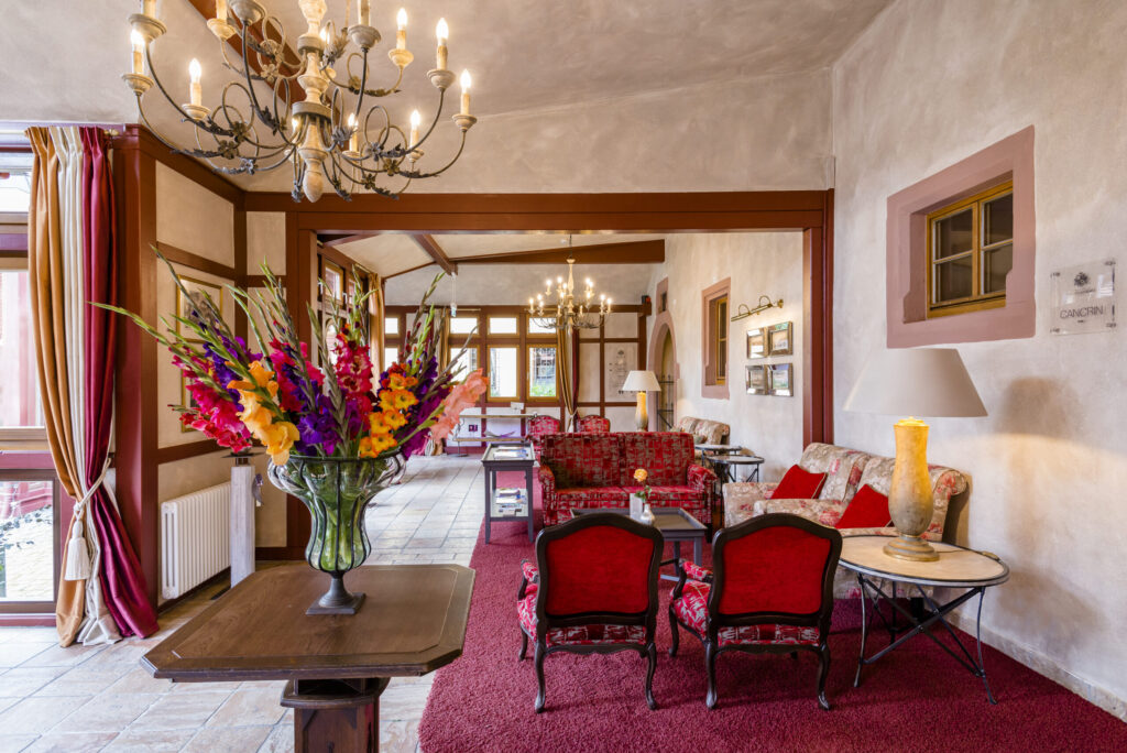 Elegante Hotellobby mit dreifarbigen Vorhängen, roten Polstermöbeln und Kronleuchtern.