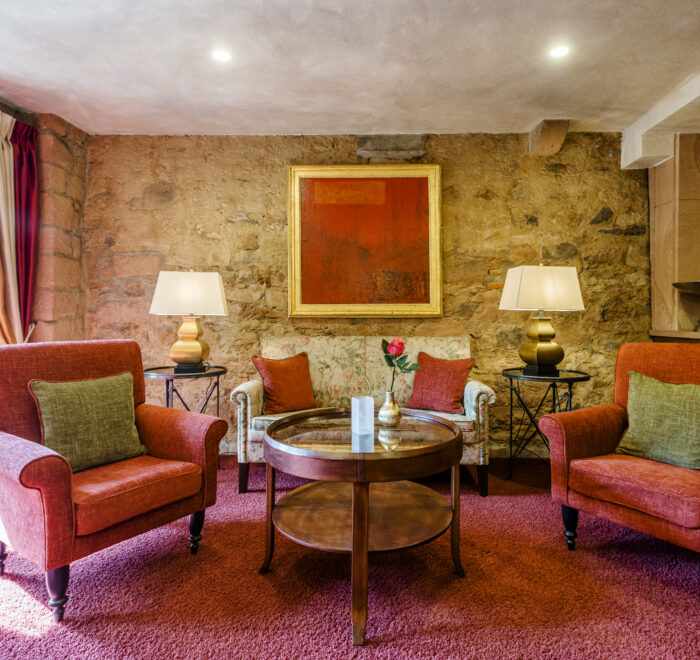 Einladende Hotellobby mit roten Polstersesseln, stilvollen Kissen und bodenlangen Vorhängen.