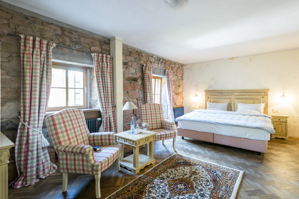 Gemütliches Landhauszimmer mit karierten Vorhängen und passenden Polstermöbeln vor rustikaler Steinwand.
