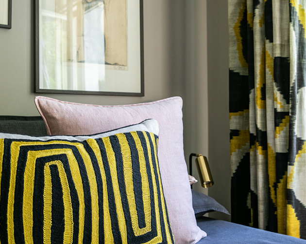 Modernes Schlafzimmer mit dekorativen Kissen und farblich abgestimmten Vorhängen.