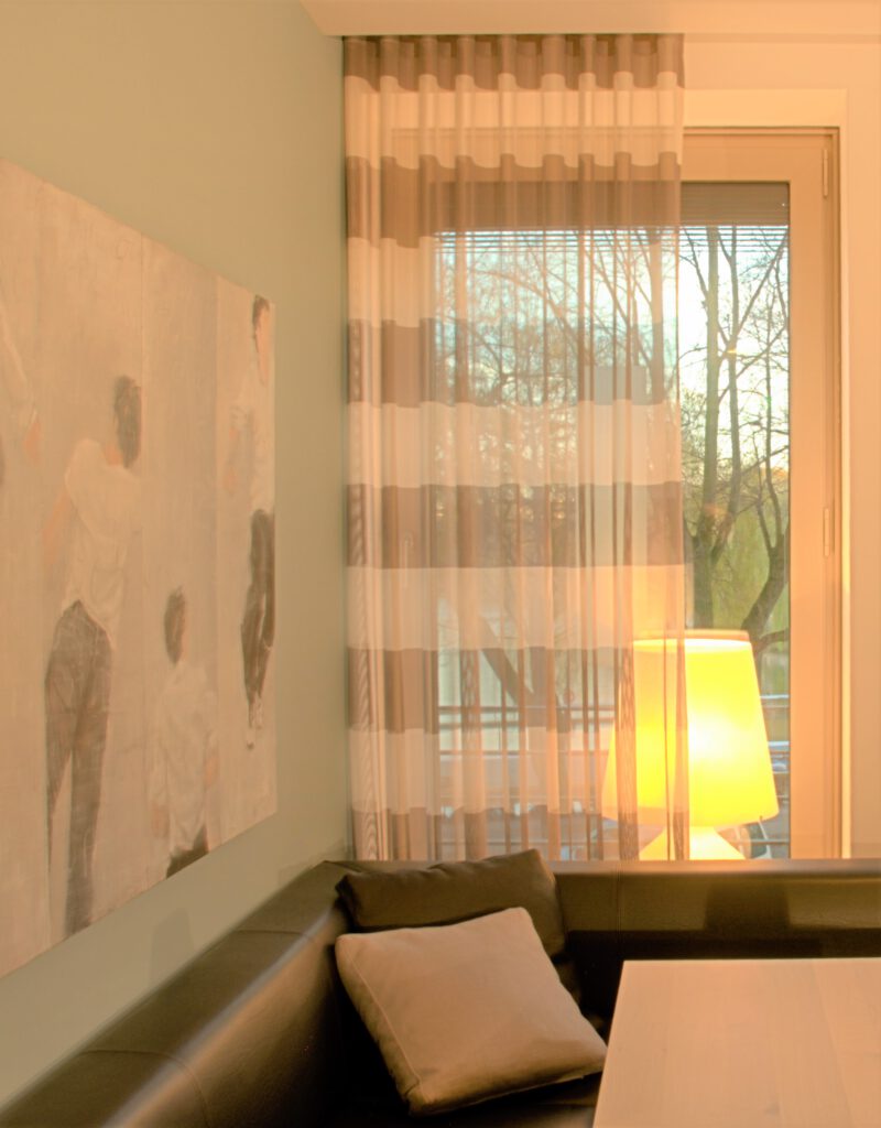 Moderner Wellenvorhang mit breiten Streifen in Beige und Weiß vor bodentiefem Fenster.