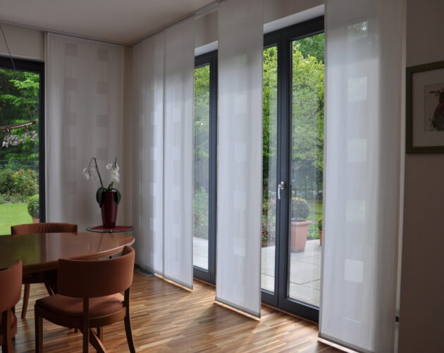 Hochwertige Flächenvorhänge mit präziser Verarbeitung und dezentem Muster in einem stilvollen Esszimmer.