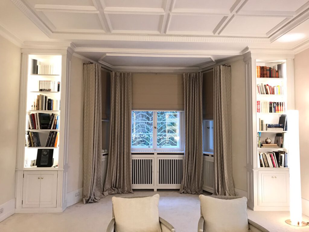 Elegantes Wohnzimmer mit bodentiefen, aufliegenden Vorhängen und perfekt fallenden Quadro Faltrollos in neutralen Farbtönen.