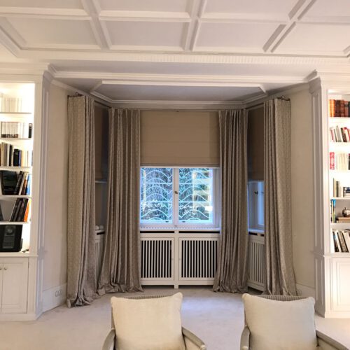 Elegantes Wohnzimmer mit bodentiefen, aufliegenden Vorhängen und perfekt fallenden Quadro Faltrollos in neutralen Farbtönen.