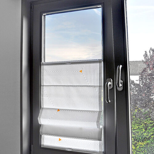 Faltrollo zum Verschieben mit geometrischem Muster in Grau und kleinen farblichen Akzenten, montiert an einem modernen Fenster mit dunklem Rahmen.