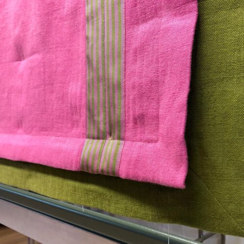 Heruntergelassenes Raffrollo in Pink mit grüner Unterlegung und Besatzstreifen in kontrastierendem Design.