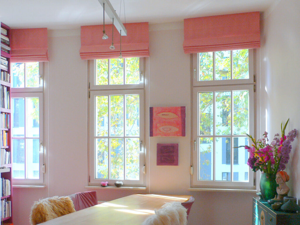 Klassische Raffrollos (Classic Faltrollos) aus rosa Leinenstoff in einem hellen und stilvollen Wohnraum.