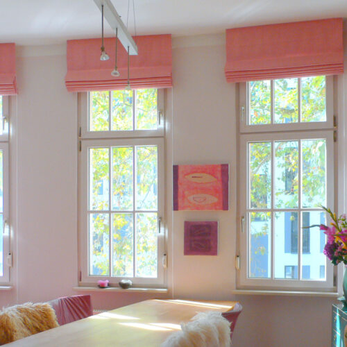 Klassische Raffrollos (Classic Faltrollos) aus rosa Leinenstoff in einem hellen und stilvollen Wohnraum.